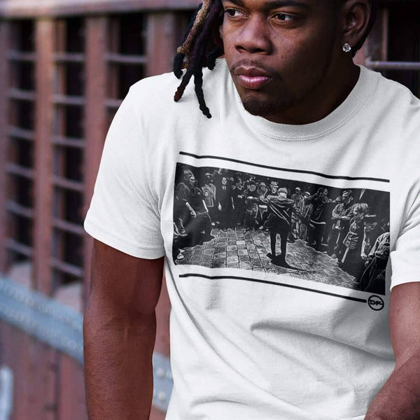 a young man with locks hair sitting on a rail wearing a tokyo bop t-shirt