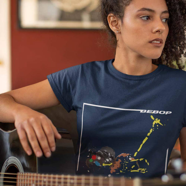 girl wearing a navy round  neck bebop jazz navy t-shirt with a trumpet player on the front and holding an acoustic guitar